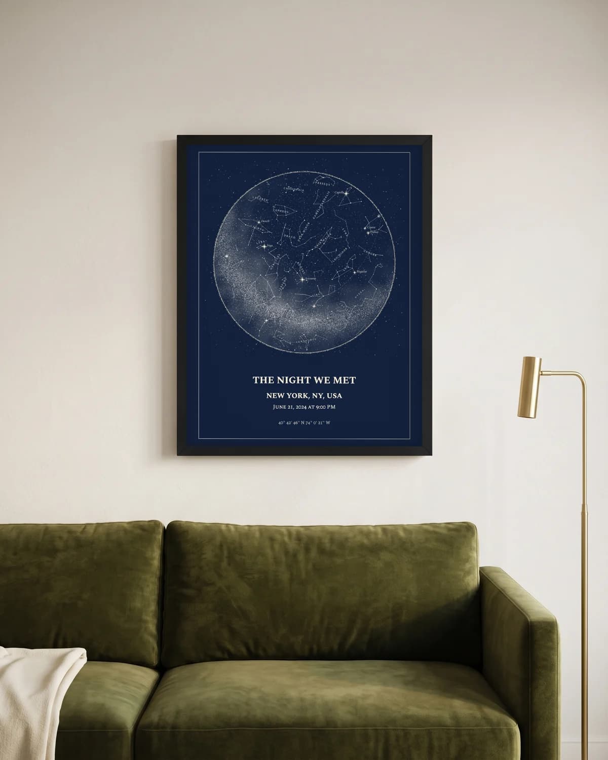 Black-framed star map poster hanging above a wooden sideboard with a brass lamp