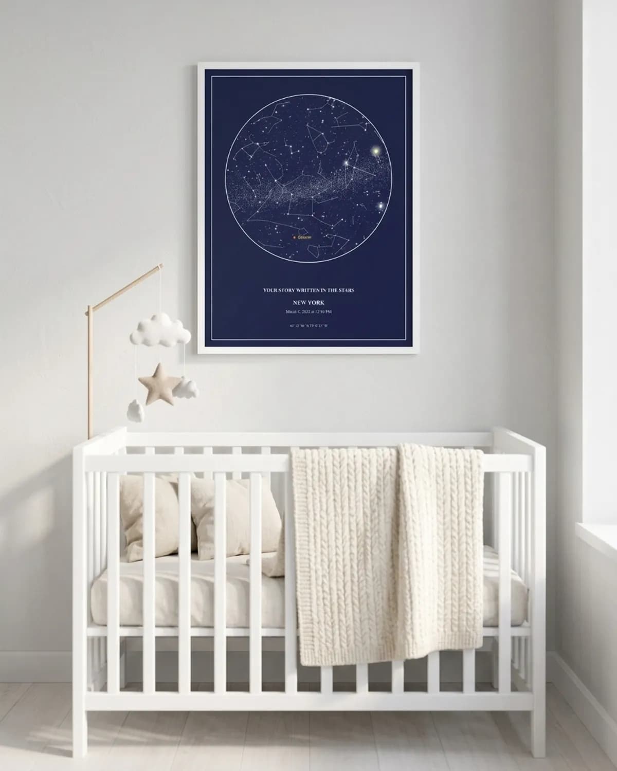 Navy star map poster in a white frame above a nursery crib