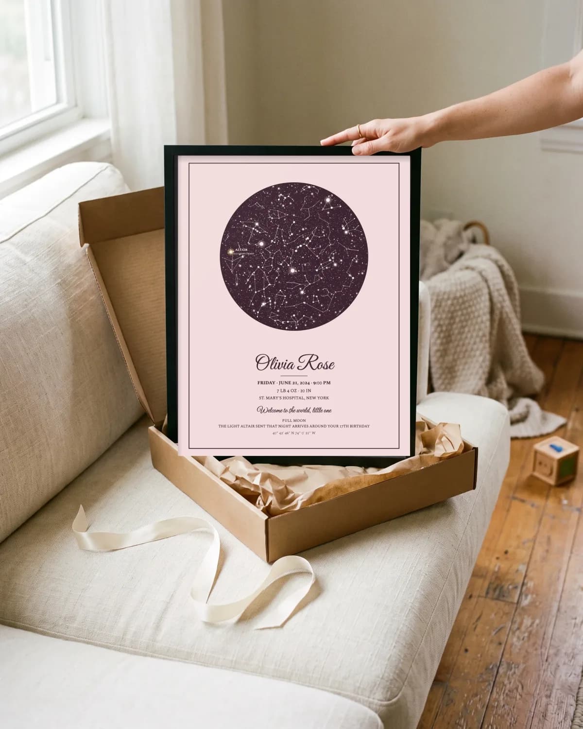 A framed birth poster unwrapped from a gift box at a baby shower