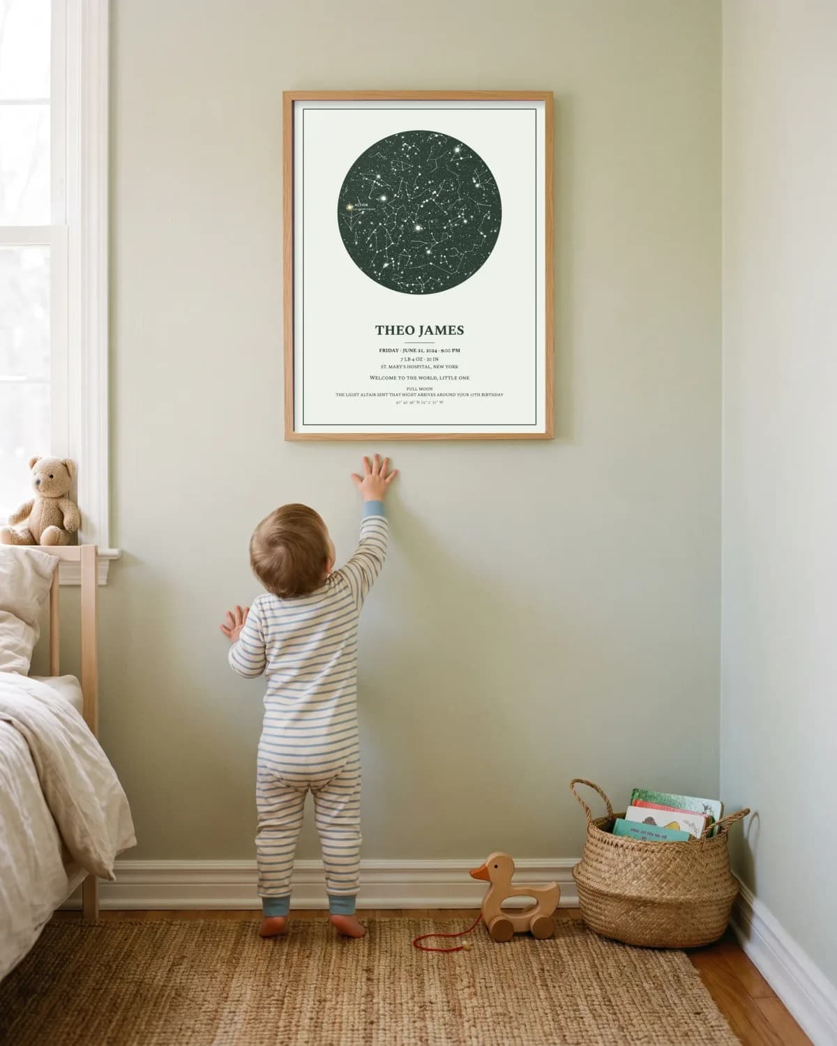 A toddler reaching up toward their birth poster on a nursery wall
