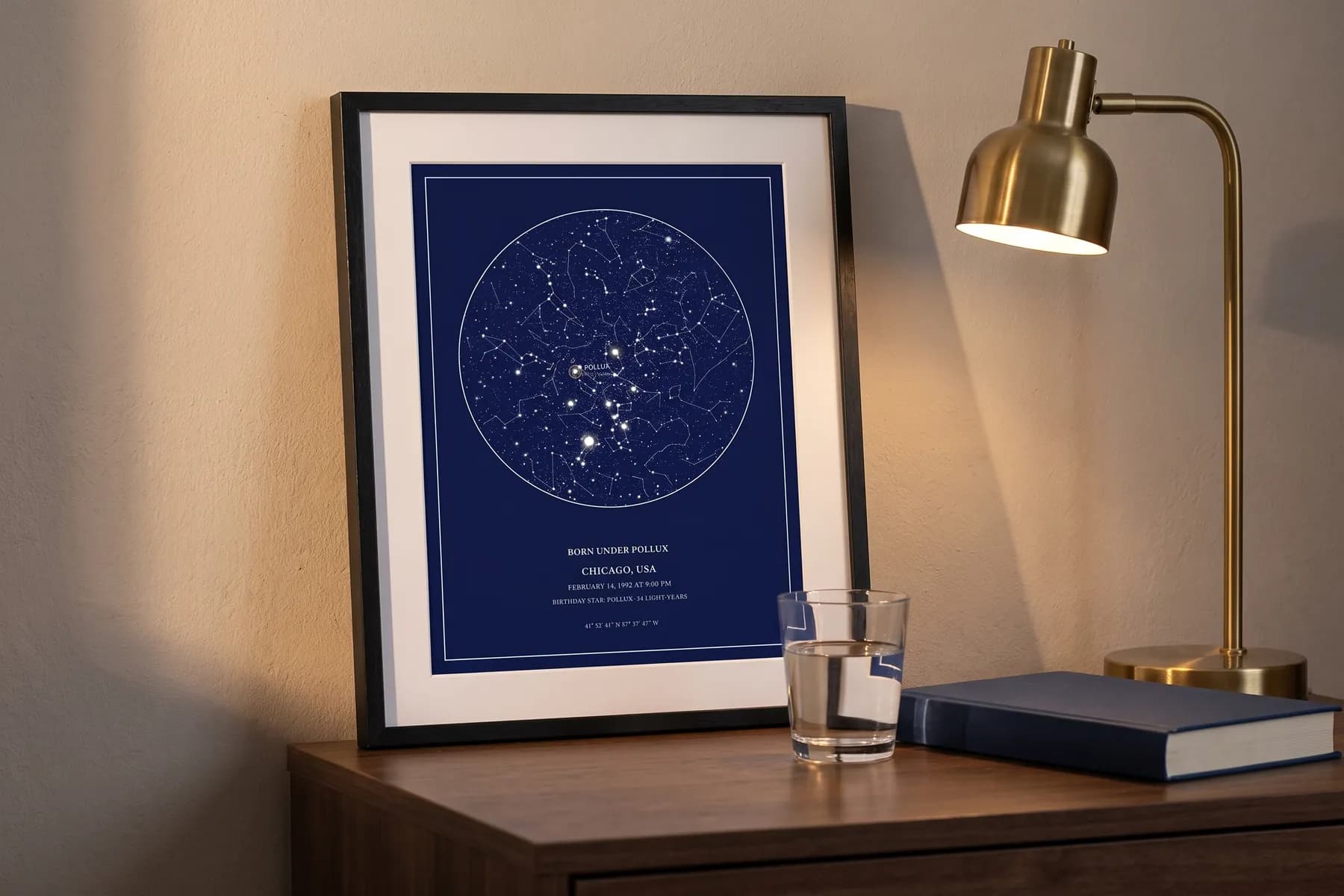 A framed star map with the birthday star named, leaning on a nightstand beside a brass lamp